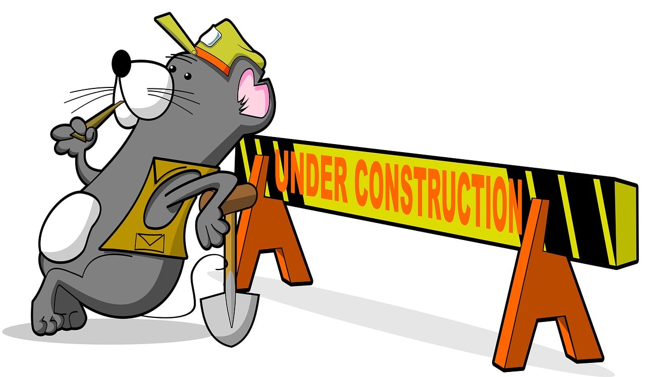 Um rato usando colete e bone amarelos, com o braço apoiado sobre uma pá e a cabeça apoiada sobre um cavalete onde está escrito under construction.